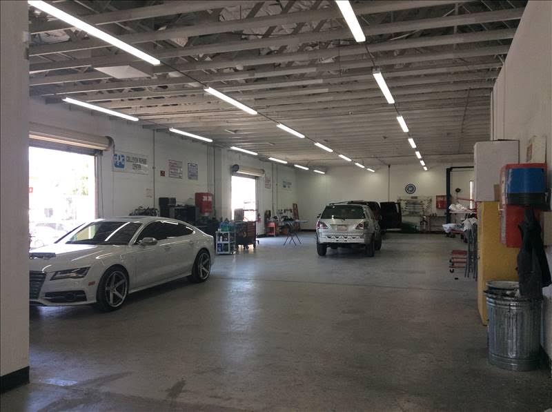 Bright indoor repair bay at Ability Auto Body with a white Audi sedan